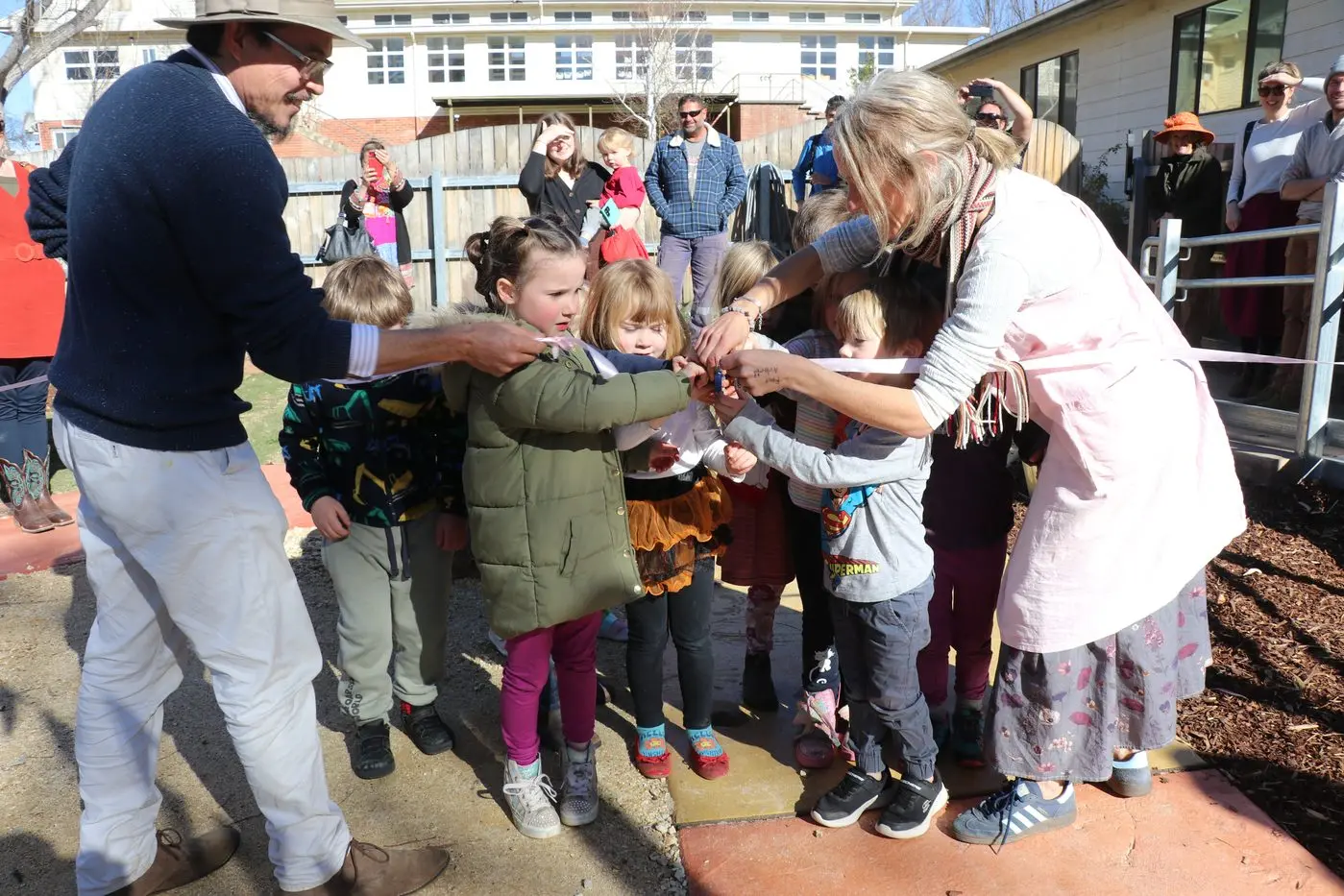 PLAY: The Alpine School kindergarten children help education manager Eric Hopf and kindergarten teacher Myolene Mesley cut the ribbon on the newly construction playground. PHOTOS: Elle Thompson